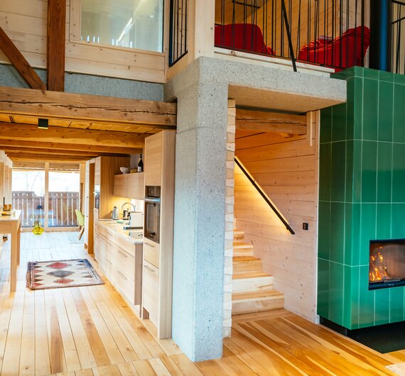 Cozy wooden cabin interior with open-plan layout, fireplace, and vibrant furnishings creating a warm, rustic atmosphere. | © Urlaub am Bauernhof Kärnten / Daniel Gollner