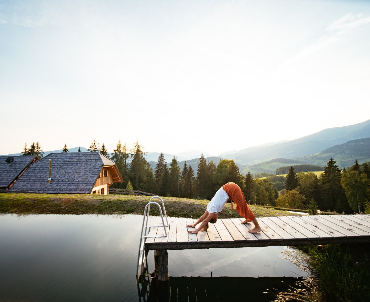 Herabschauender Hund beim Yoga am Steg | © Urlaub am Bauernhof Steiermark / Daniel Gollner Adho Mukha Svanasana am Hüttensteg beim urlaub auf der Alm | © Urlaub am Bauernhof Steiermark / Daniel Gollner