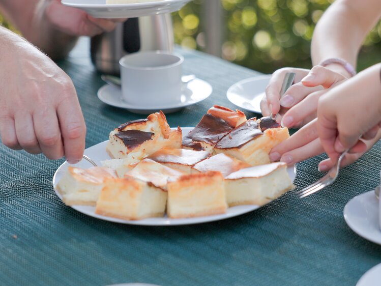 People sharing a dessert with different cake slices on a table outdoors.