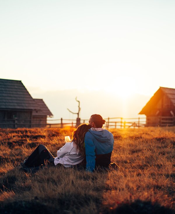 Couple with sunset | © Urlaub am Bauernhof Kärnten / Daniel Gollner Couple sits on the meadow and enjoys the sunset | © Urlaub am Bauernhof Kärnten / Daniel Gollner