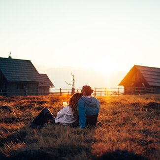 Couple sits on the meadow and enjoys the sunset | © Urlaub am Bauernhof Kärnten / Daniel Gollner