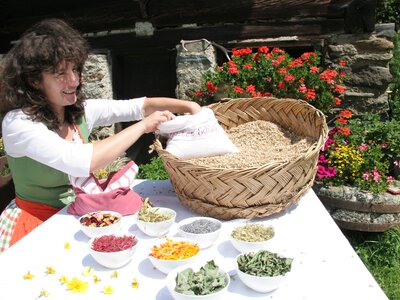 Bäuerin steht beim Tisch mit Blüten und Getreide | © Urlaub am Bauernhof Kärnten / Ernst Peter Prokop