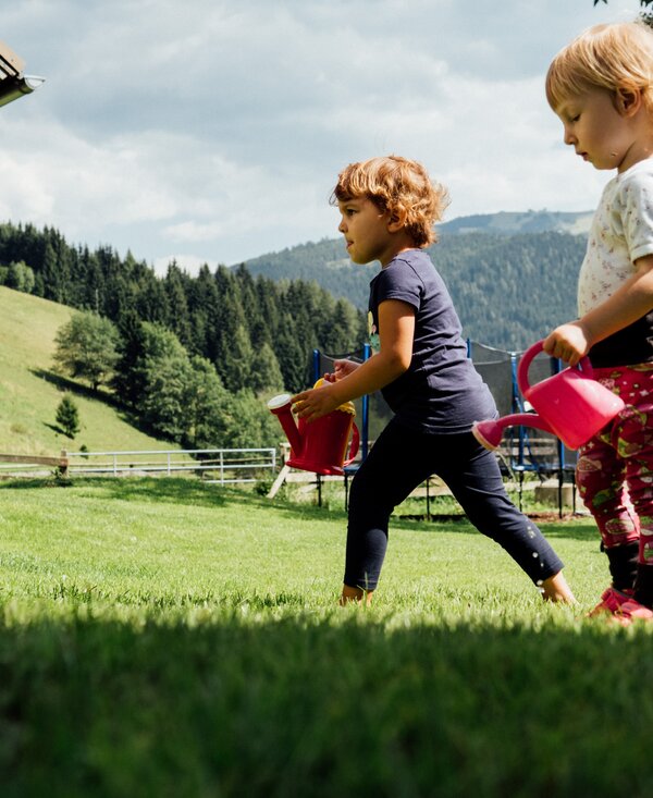 Kinder mit Gießkannen auf der Wiese | © Urlaub am Bauernhof Kärnten / Daniel Gollner