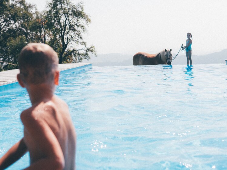 Kind im Pool und Mädchen mit Pony | © Urlaub am Bauernhof Kärnten / Daniel Gollner