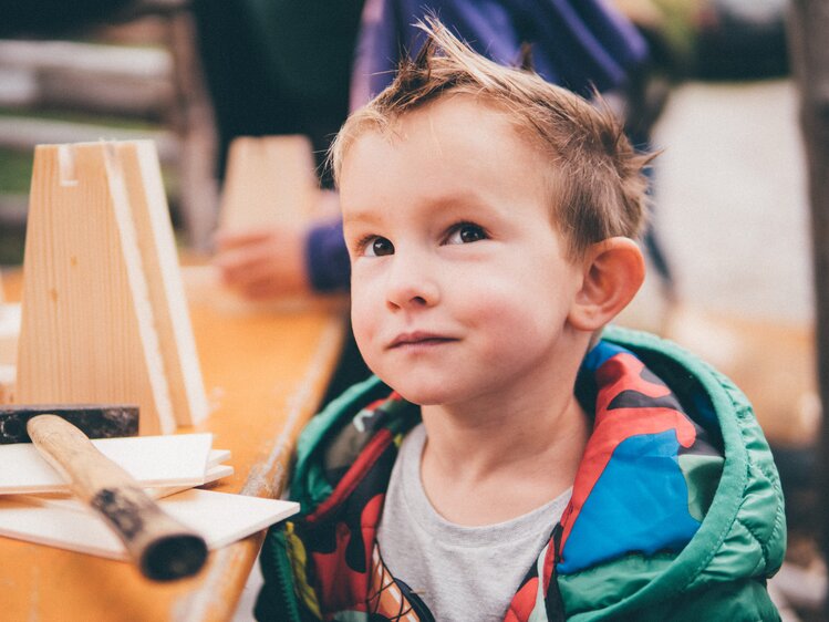Bub mit Holz und Werkzeug am Tisch | © Urlaub am Bauernhof Kärnten / Daniel Gollner