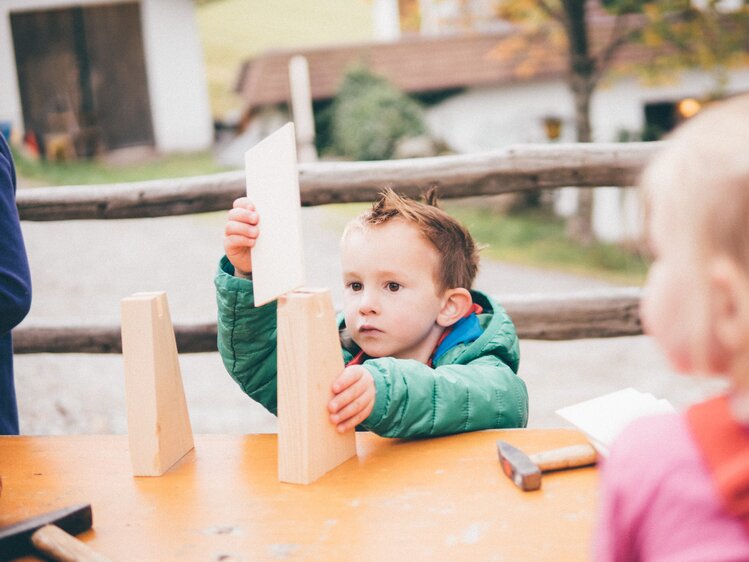 Kind am Tisch bastelt mit Holz | © Urlaub am Bauernhof Kärnten / Daniel Gollner