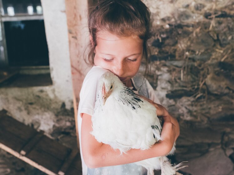 Mädchen hält das Huhn im Arm | © Urlaub am Bauernhof Kärnten / Daniel Gollner