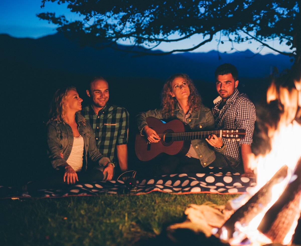 Familie mit Gitarre | © Urlaub am Bauernhof Kärnten/ Daniel Gollner Familie sitzt mit der Gitarre beim Lagerfeuer | © Urlaub am Bauernhof Kärnten/ Daniel Gollner