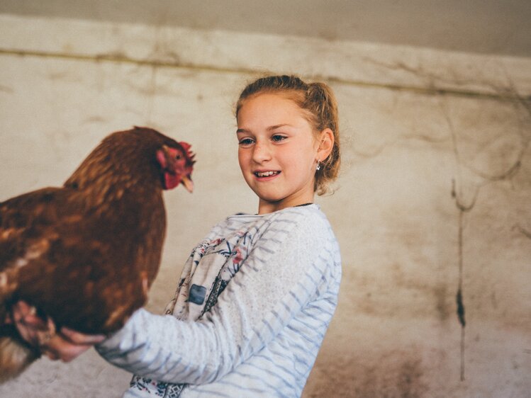 Mädchen hält das Huhn in der Hand | © Urlaub am Bauernhof Kärnten / Daniel Gollner
