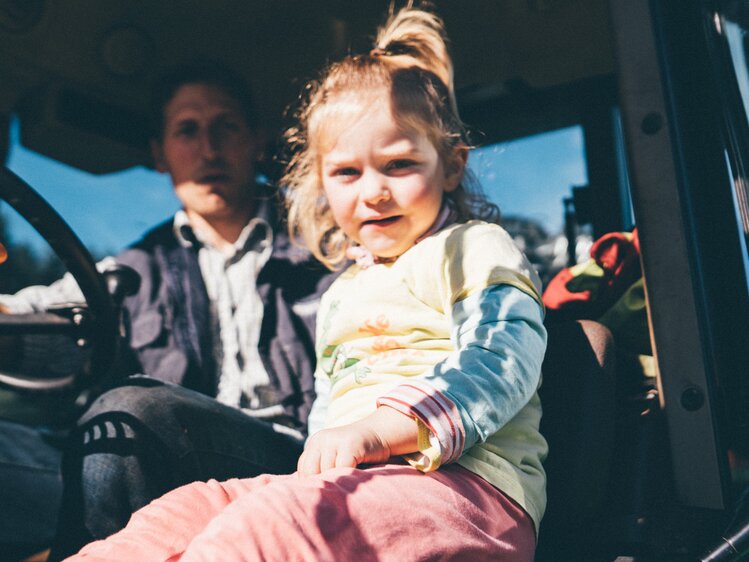 Mädchen und Mann sitzen im Traktor | © Urlaub am Bauernhof Kärnten / Daniel Gollner
