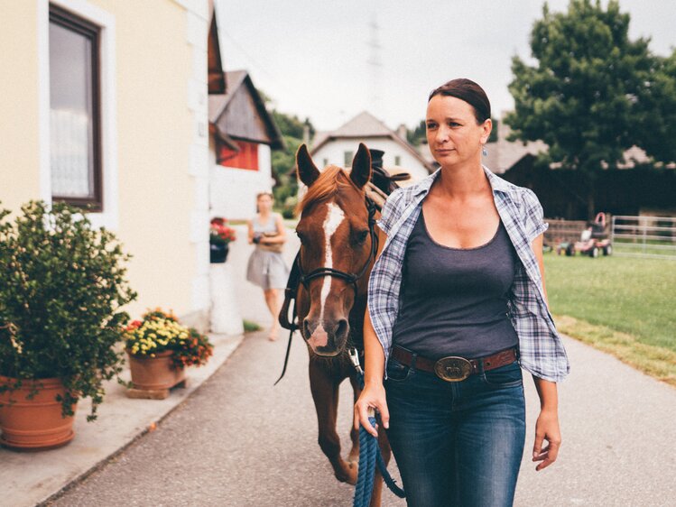 Frau führt das Pferd am Weg | © Urlaub am Bauernhof Kärnten / Daniel Gollner