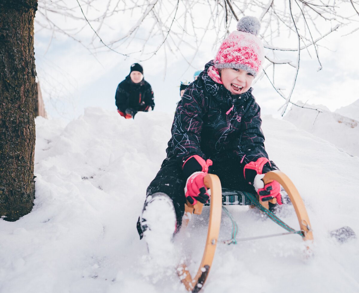 Kind sitzt auf dem Schlitten im Schnee | © Urlaub am Bauernhof Kärnten/ Daniel Gollner