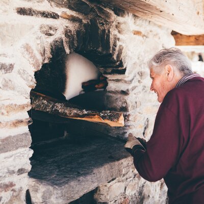 Bäuerin beim Ofen | © Urlaub am Bauernhof Kärnten / Daniel Gollner Bäuerin gibt Holz in den Ofen | © Urlaub am Bauernhof Kärnten / Daniel Gollner