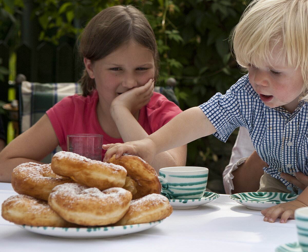 Leckere Bauernkrapfen | © Urlaub am Bauernhof Oberösterreich / Uli Matscheko Kind greift auf einem Teller mit Bauernkrapfen zu | © Urlaub am Bauernhof Oberösterreich / Uli Matscheko