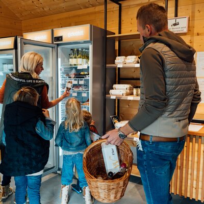 Family shopping in a supermarket, children with adults in front of a fridge with beverages.