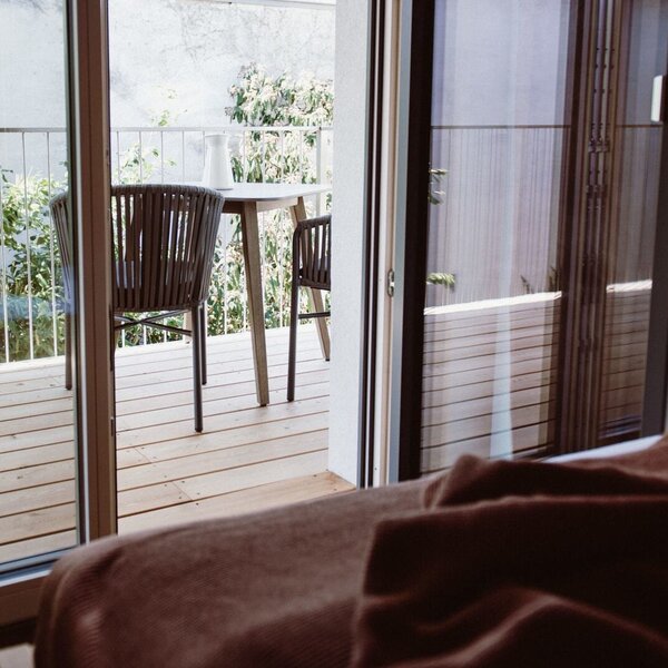 Balcony of the farmhouse room with a wooden deck, outdoor seating, and garden views.