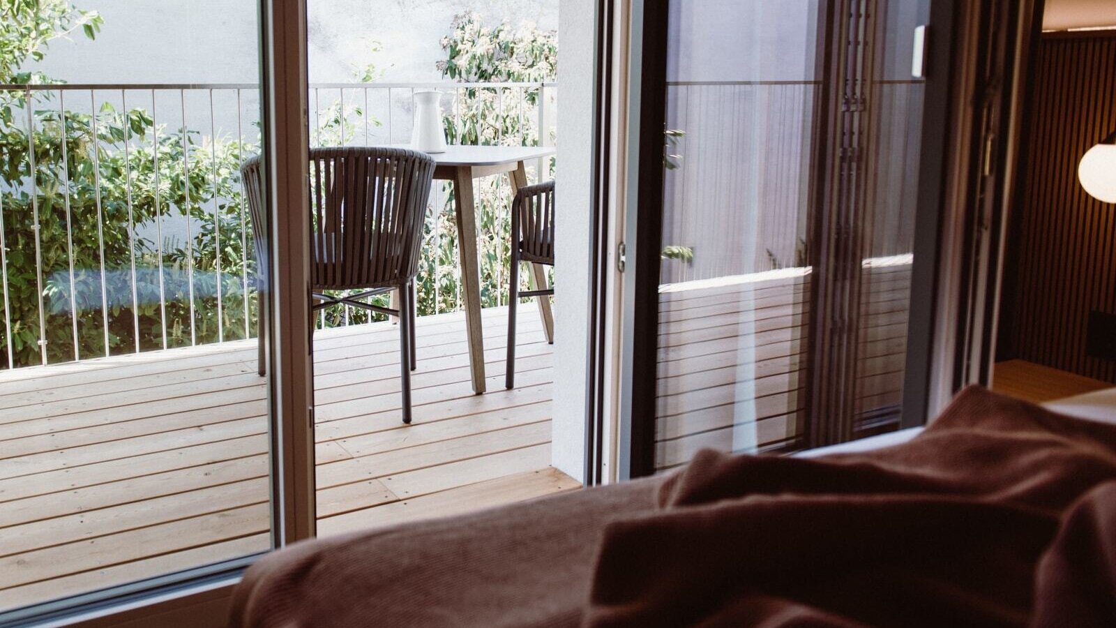 Balcony of the farmhouse room with a wooden deck, outdoor seating, and garden views.