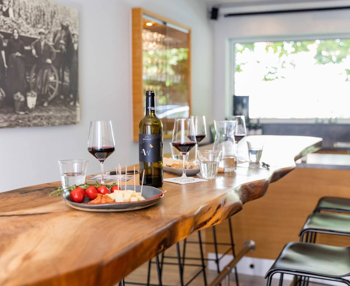 Wine tasting area of the winery, featuring a wooden counter, wine bottles, glasses, and snacks.
