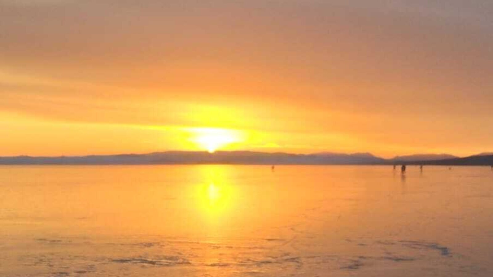 An atmospheric sunset over the wide, icy lake near the farmhouse.