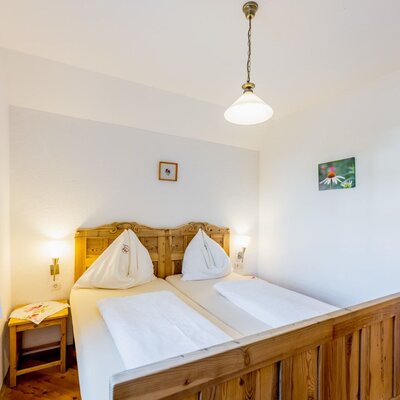 Bedroom in the farmhouse with a wooden double bed, nightstands, and wooden floor.