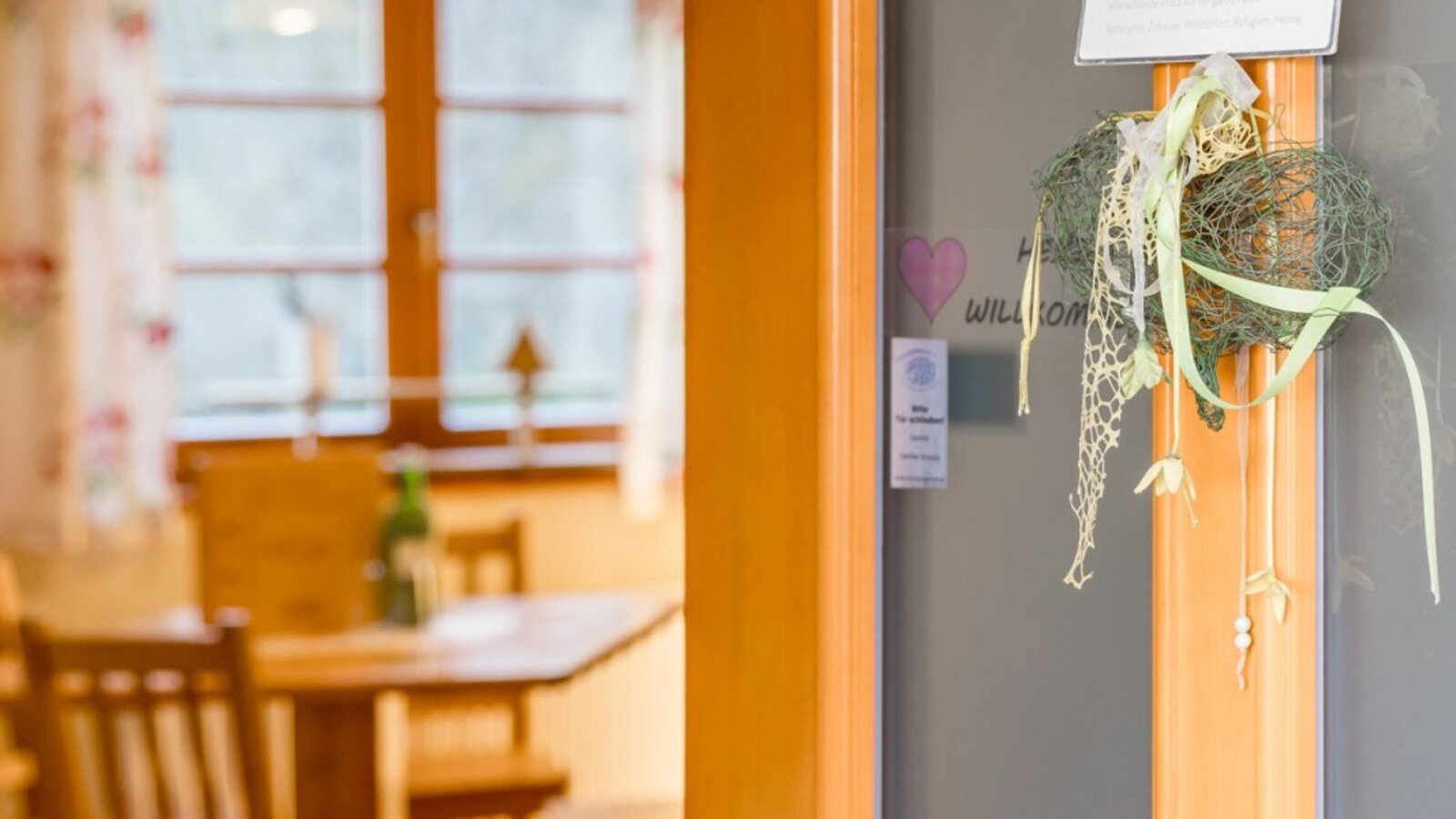 Open door to the farmhouse dining area with a wooden table and chairs, adorned with a 'favorite spot' sign.