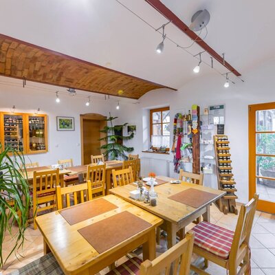 The dining area of the farmhouse with wooden tables, chairs, a brick vaulted ceiling, product display, and a view of the outdoor area.
