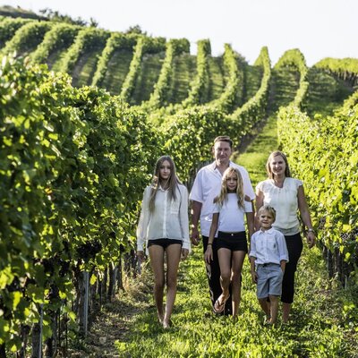 A family walking through the rows of the farmhouse's vineyard.