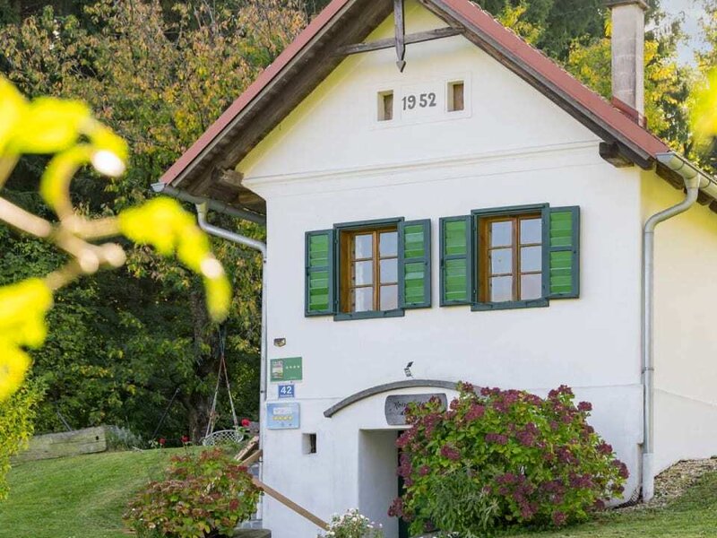 The farmhouse's charming outbuilding with traditional green shutters and a well-kept green lawn.