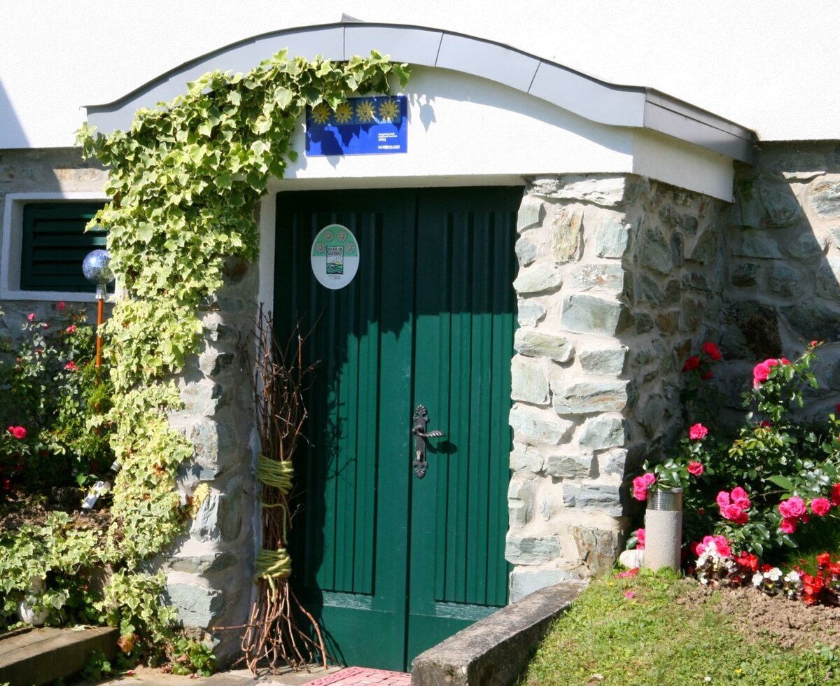 The farmhouse entrance features a green wooden door, stone facade, ivy, flowering bushes, and a three-star rating sign above.