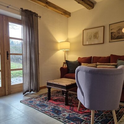 Living area in the farmhouse featuring a sofa, armchair, coffee table, and double doors with direct garden access.