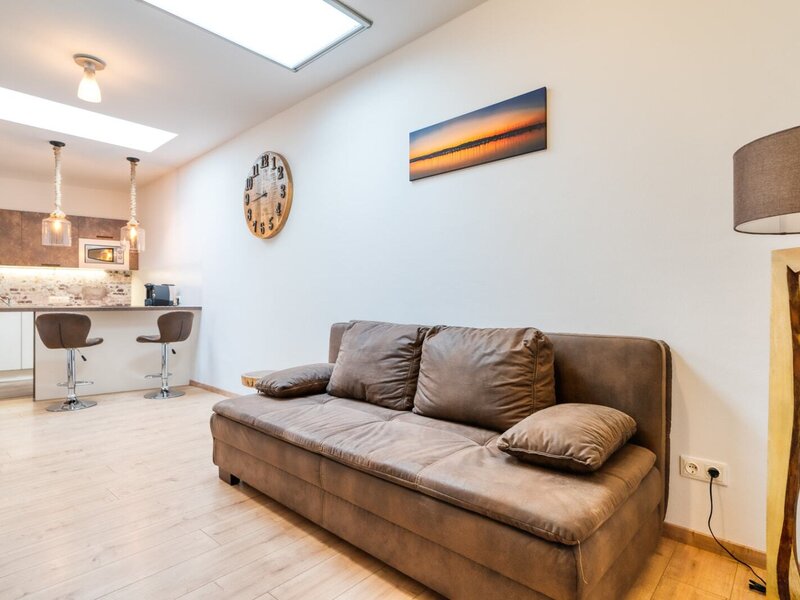 The farmhouse's living area features a sofa, a kitchen counter with two bar stools, and overhead skylights.