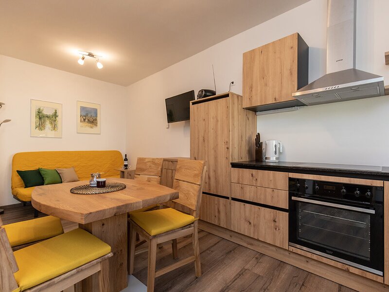 The combined living and dining area in the "Schüttkasten" with a perfectly equipped kitchenette, cozy dining area, and a sofa for watching TV