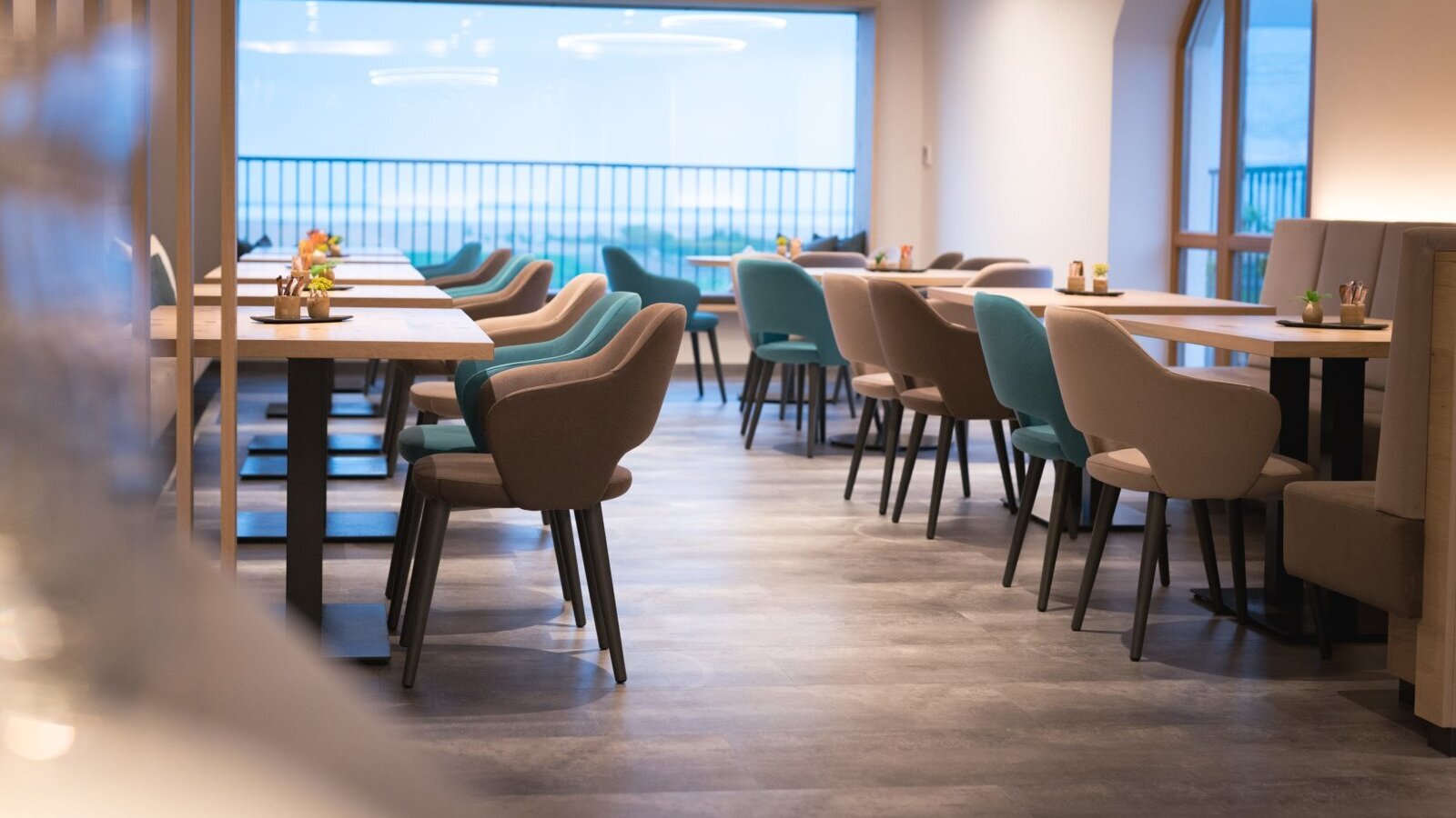 The dining and lounge area at the farmhouse offers various tables and seating arrangements, with large windows providing natural light and views.