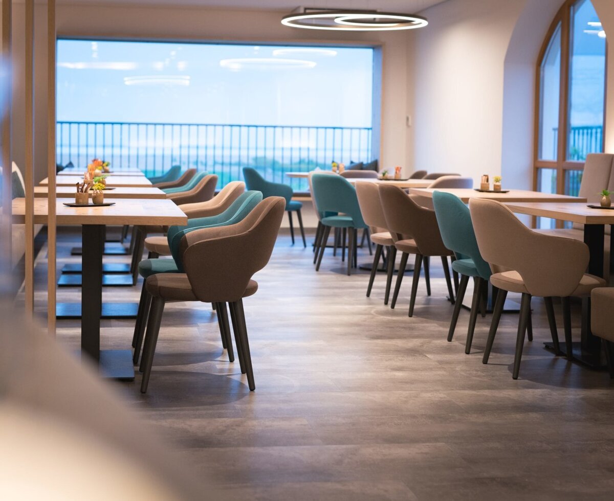 The dining and lounge area at the farmhouse offers various tables and seating arrangements, with large windows providing natural light and views.