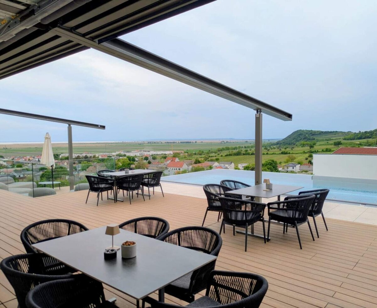 The farmhouse terrace with tables, chairs, and an infinity pool offers a view of the landscape and the lake.