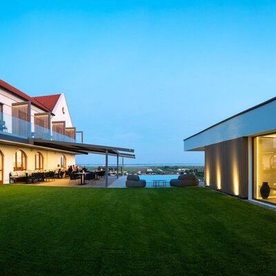 The farmhouse's outdoor area featuring a terrace, infinity pool, a lawn, and the modern wellness area.