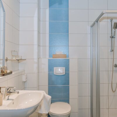 Bathroom in the Haus with a sink, mirror, toilet, and shower cabin.