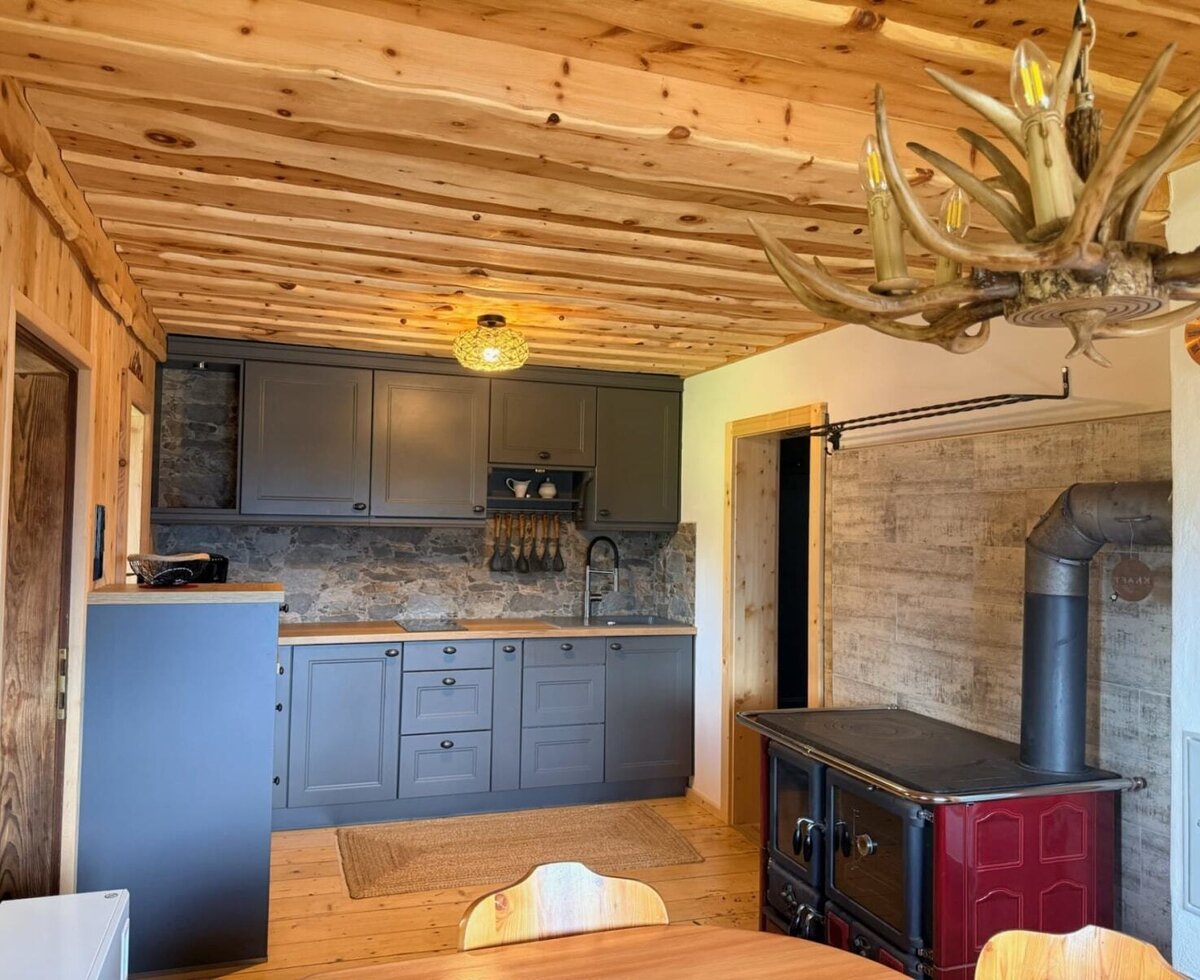 The stylish kitchen combines warm wooden elements, a modern fitted kitchen and a traditional wood-burning range.