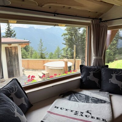 In the Zirben Room, a cosy window seat invites you to linger while overlooking the mountains, the private wood-fired hot tub and the separate sauna house on the terrace.