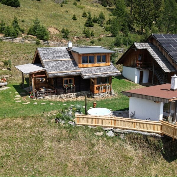 Overall view of Almchalet Kampleck with its private sauna house, hot tub and terrace, nestled in the peaceful alpine surroundings.