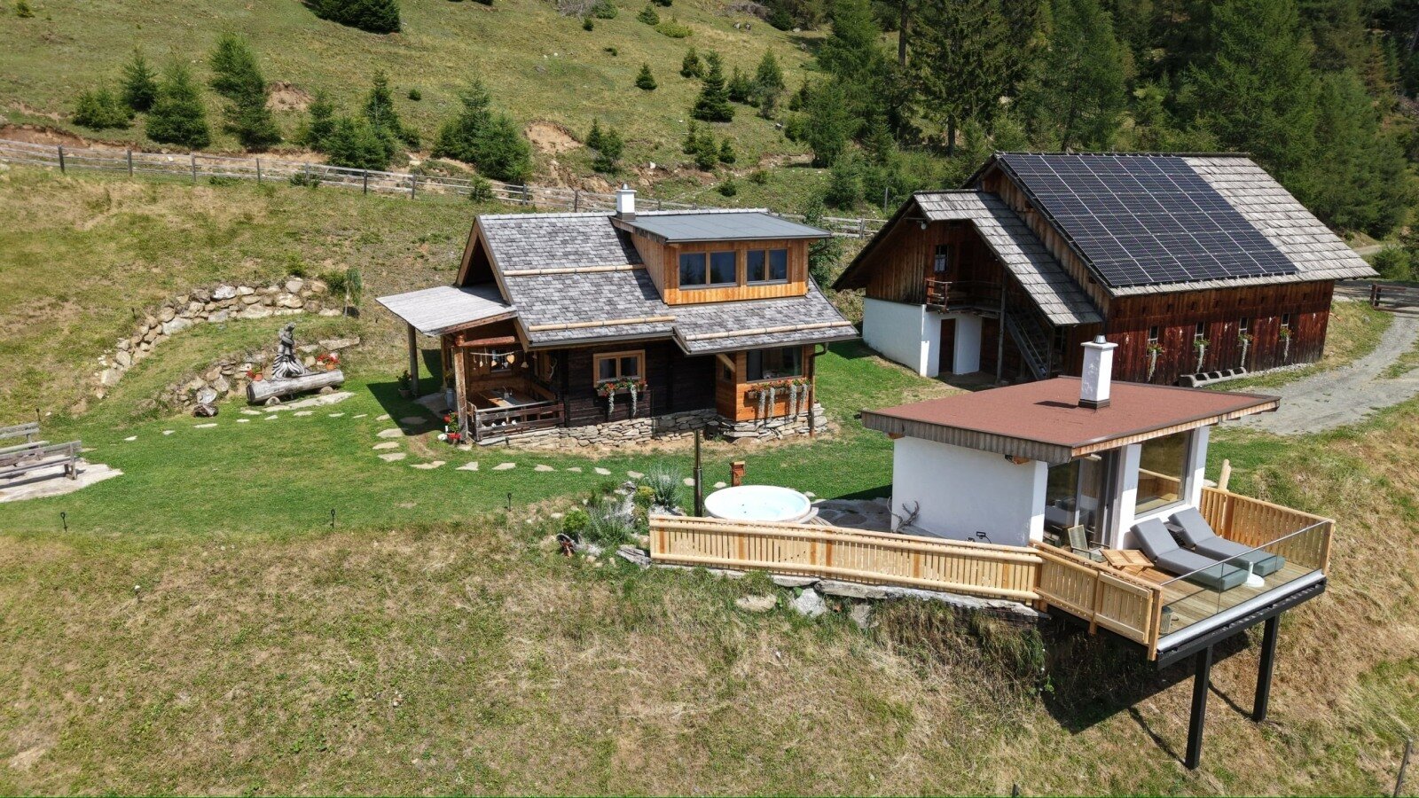 Overall view of Almchalet Kampleck with its private sauna house, hot tub and terrace, nestled in the peaceful alpine surroundings.