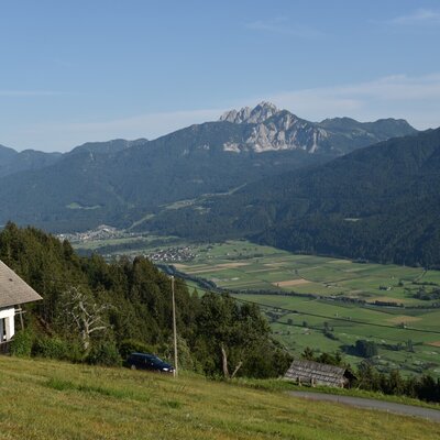 The Alpine Hut on a grassy slope with views of the valley, a village, and a mountain range.