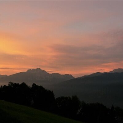 Mountain views from the Alpine Hut at sunset, featuring an orange and pink sky.