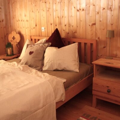 Bedroom with wooden walls, a double bed, and two bedside tables.