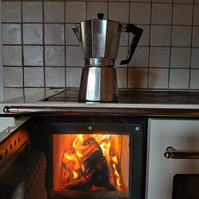 Moka pot on the wood-burning stove with visible fire in the Bed and Breakfast.
