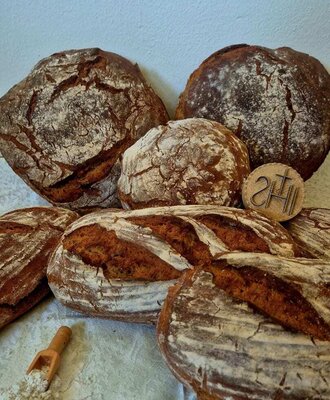 Freshly baked bread loaves, some dusted with flour, offered at the Alm.