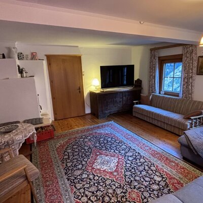 Relax in the cozy living area of this Alpine Hut, featuring comfortable sofas, a flat-screen TV, and a warm fireplace.