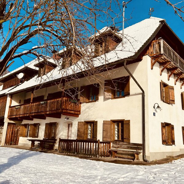 The vacation rental exterior, featuring multiple wooden balconies, window shutters, and a snow-covered roof, surrounded by snow.