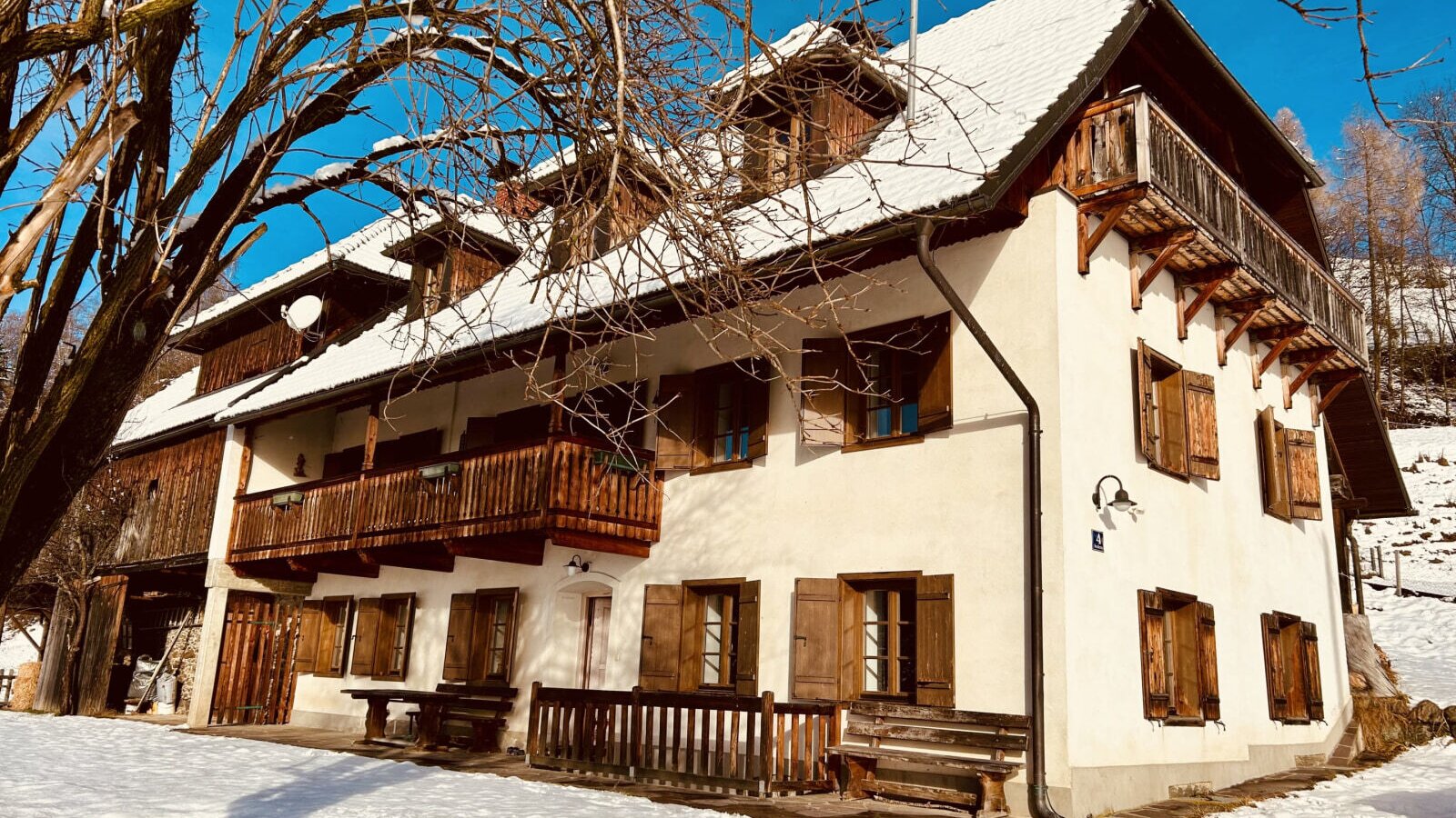 The vacation rental exterior, featuring multiple wooden balconies, window shutters, and a snow-covered roof, surrounded by snow.