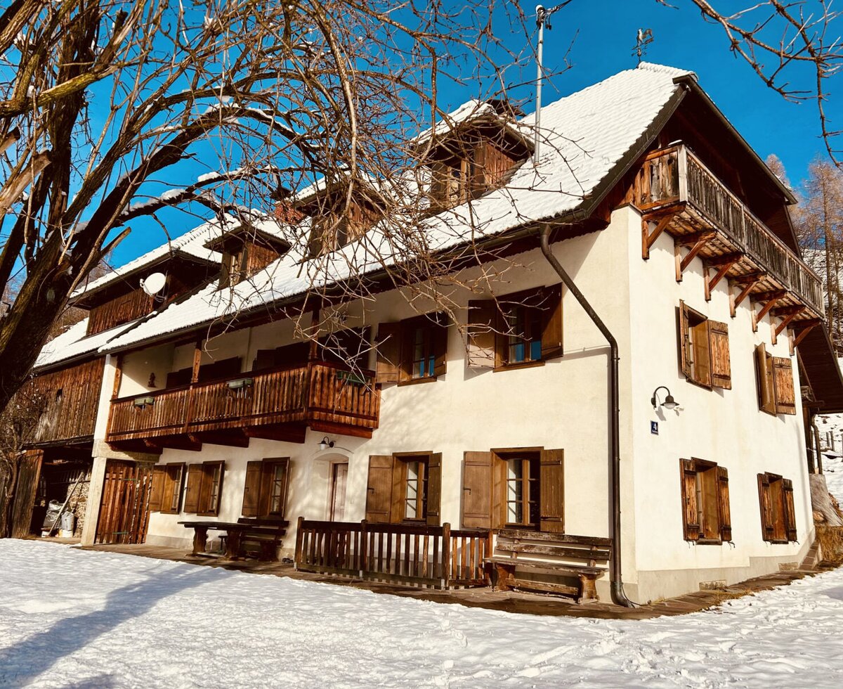 The vacation rental exterior, featuring multiple wooden balconies, window shutters, and a snow-covered roof, surrounded by snow.